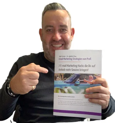 Ralf Schmitz zeigt lächelnd auf den gedruckten Report 7 E-Mail Marketing Hackz