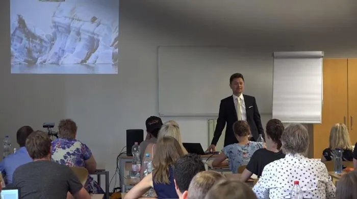 Maxim Mankevich spricht im Psychologiemaster Seminar vor Teilnehmern, im Hintergrund eine Projektion