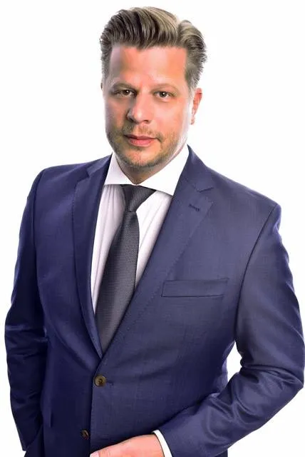 Alex Düsseldorf Fischer im dunkelblauen Anzug mit Krawatte vor weißem Hintergrund