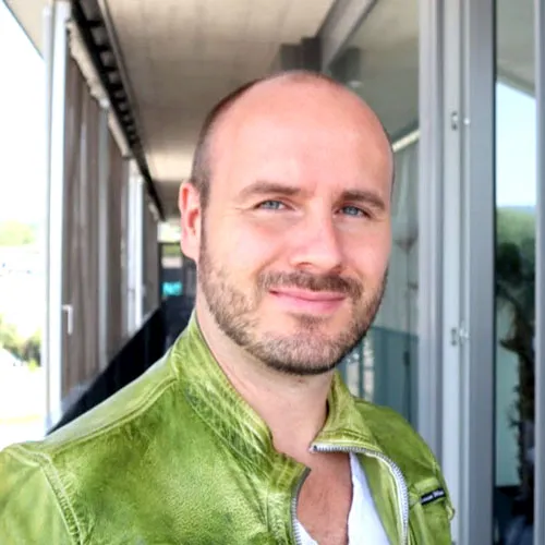 Alexander Raue in grüner Lederjacke vor einer Glasfassade