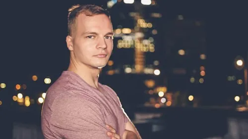 Alexander Wahler mit verschränkten Armen vor einer nächtlichen Stadtkulisse