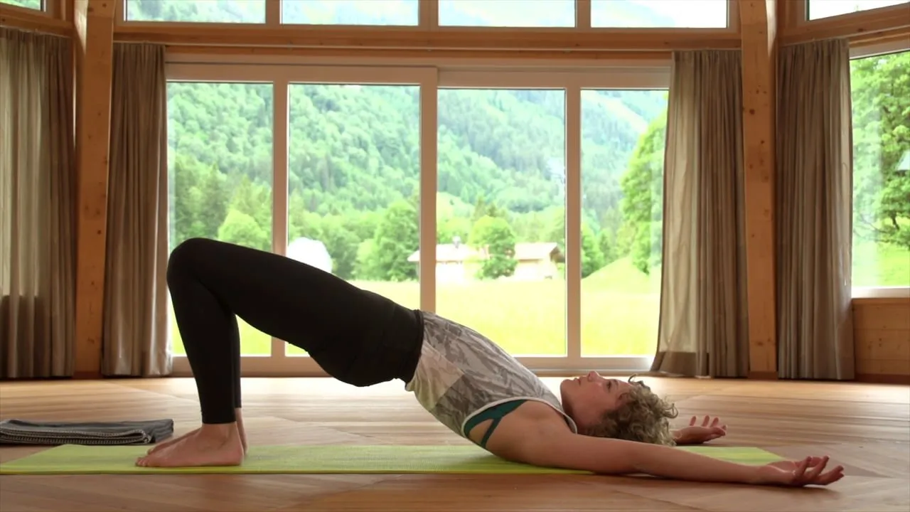 Yogaübung Brücke in einem Holzsaal mit Bergblick, Standbild aus dem Informationsvideo zum Ayur-Yoga Basis-Kurs