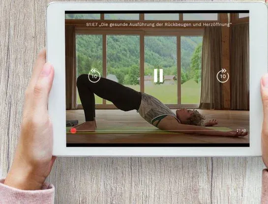 Tablet mit einem Kursvideo des Ayur-Yoga Basis-Kurses, im Bild eine Rückbeuge in einem Saal mit Bergblick