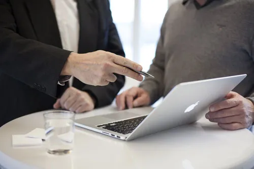 Zwei Geschäftsleute besprechen sich an einem Laptop – Symbolbild für das Bestseller Training von Dirk Kreuter