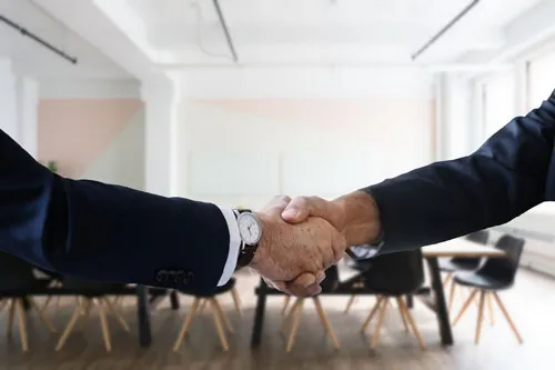 Handschlag zweier Geschäftsleute in einem hellen Büro – Symbolbild für Neukundengewinnung im Bestseller Training