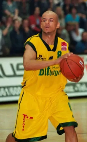 Cecil Egwuatu als Basketballspieler im gelben Trikot mit dem Ball in der Hand