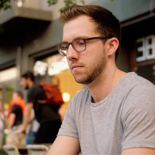 Christopher Hauffe mit Brille und grauem T-Shirt blickt nach unten