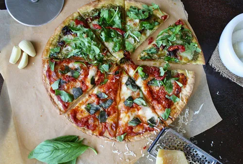 Pizza mit Rucola, Tomaten und Parmesan auf Backpapier als Beispiel für Genuss beim MAXIMUMPRINZIP