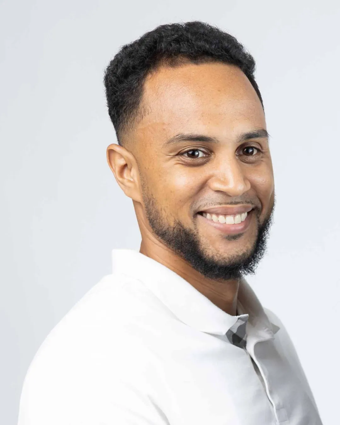 Porträtfoto von Cyril Obeng in weißem Poloshirt vor hellem Hintergrund