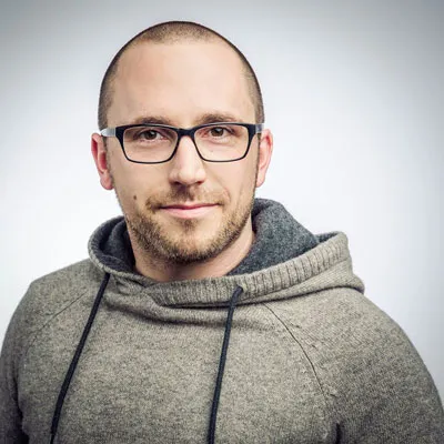 Porträt von Daniel Gaiswinkler, Gründer der Teemoney Academy, mit Brille und grauem Kapuzenpullover
