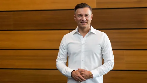 Dawid Przybylski im weißen Hemd vor einer Holzwand
