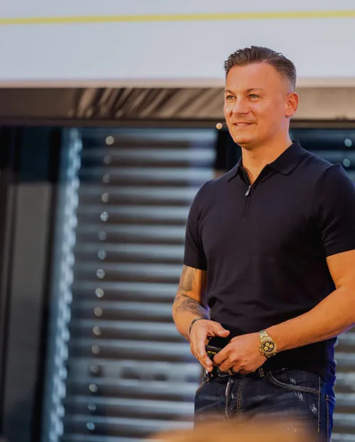 Dawid Przybylski im schwarzen Poloshirt steht lächelnd auf einer Bühne