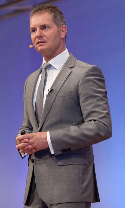 Dirk Kreuter im grauen Anzug mit Headset bei einem Vortrag auf der Bühne
