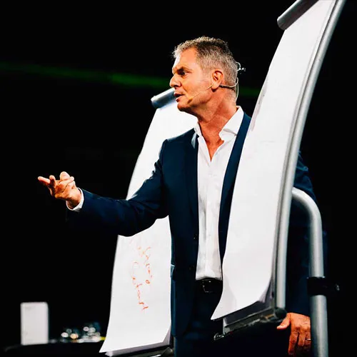 Dirk Kreuter spricht mit Headset vor einem Flipchart auf der Bühne