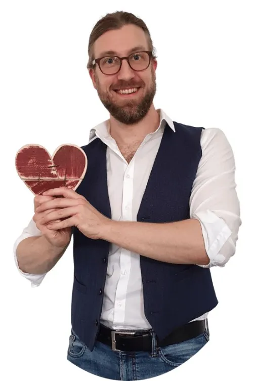 Dr. Stephan Kraft von Szenario-Zwei mit Brille und Weste hält ein rotes Herz
