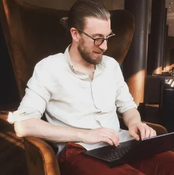 Dr. Stephan Kraft sitzt mit Laptop in einem Sessel