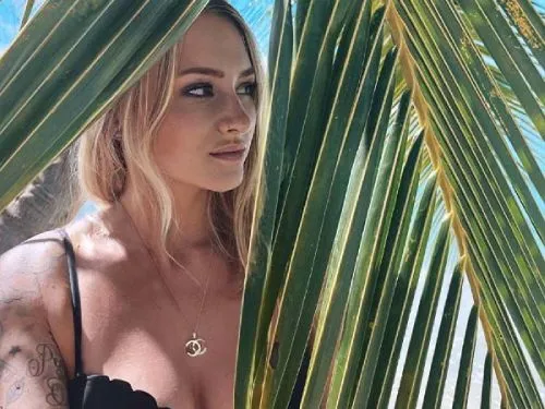 Ella von Passion Island zwischen grünen Palmblättern