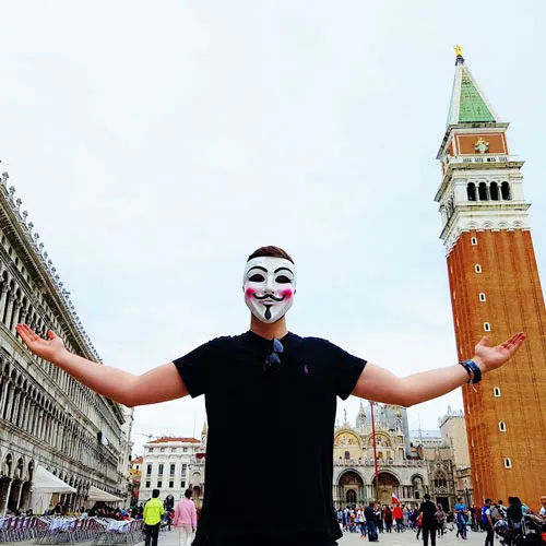 Flo Pharell mit weißer Maske und ausgebreiteten Armen auf dem Markusplatz in Venedig