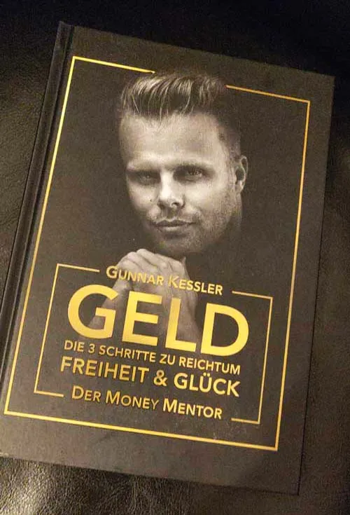Das Buch GELD von Gunnar Kessler steht aufgestellt auf einem Holztisch