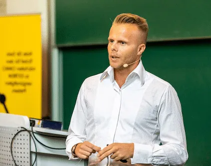 Gunnar Kessler im weißen Hemd mit Headset-Mikrofon bei einem Vortrag