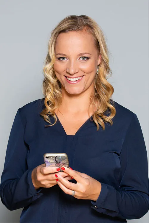 Janaina von Moos lächelnd in dunkelblauer Bluse mit dem Smartphone in der Hand