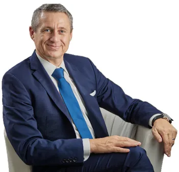 Jürgen Wechsler im blauen Anzug entspannt in einem weißen Sessel sitzend