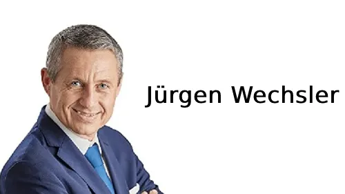 Lächelnder Jürgen Wechsler im blauen Anzug neben dem Schriftzug Jürgen Wechsler