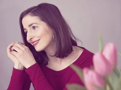 Katharina Tempel von Glücksdetektiv im roten Oberteil neben rosa Tulpen