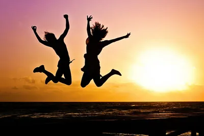 Silhouetten zweier Menschen springen vor Freude vor einem Sonnenuntergang – Symbolbild zum Lebensstarter Kurs