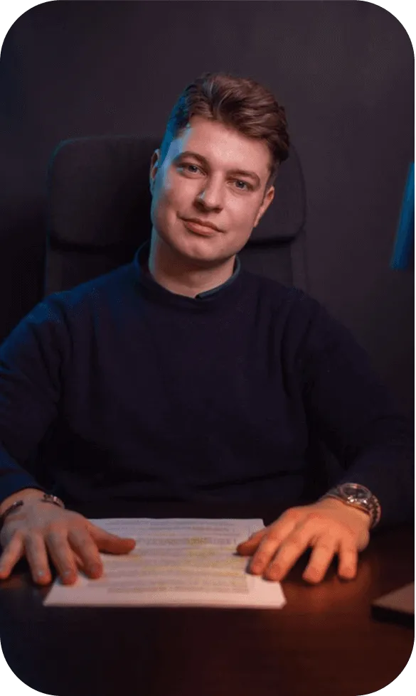 Porträtfoto von Leon Weidner am Schreibtisch im dunklen Pullover