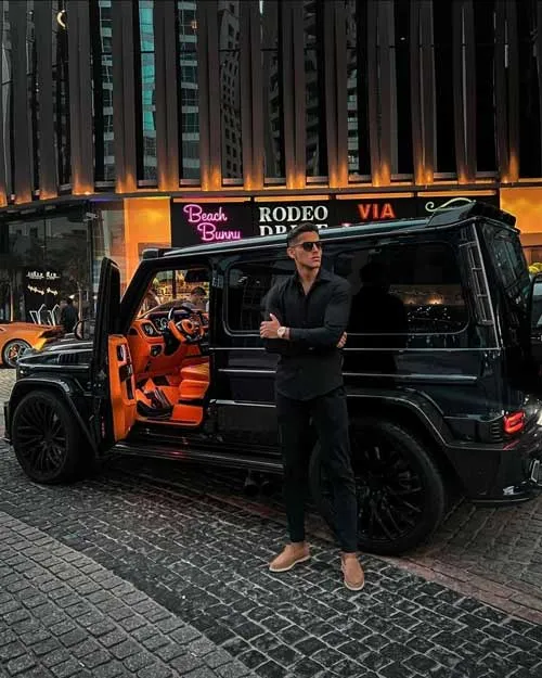 Manjeet Singh Sangha steht nachts vor einer schwarzen Mercedes G-Klasse mit geöffneter Tür