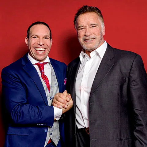 Marc Galal und Arnold Schwarzenegger beim Händedruck vor rotem Hintergrund