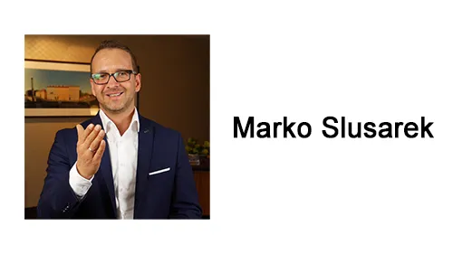 Marko Slusarek im dunkelblauen Sakko neben dem Schriftzug Marko Slusarek
