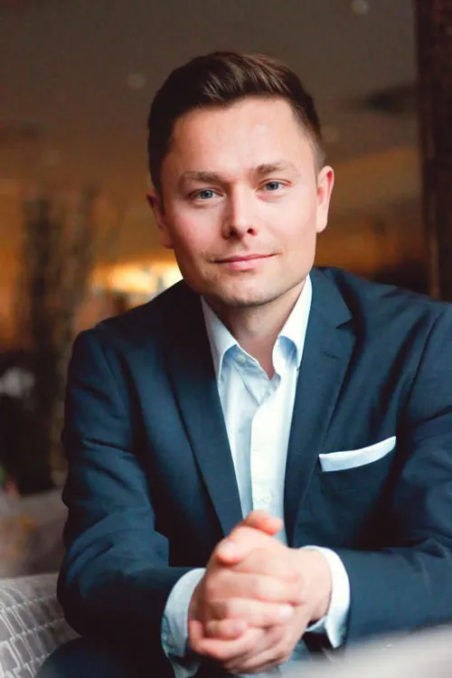 Porträt von Maxim Mankevich im dunkelblauen Anzug mit gefalteten Händen