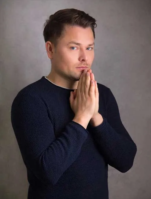 Porträt von Maxim Mankevich im dunkelblauen Pullover mit aneinandergelegten Händen