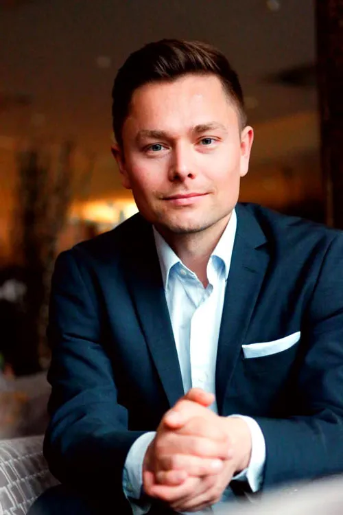 Porträt von Maxim Mankevich im dunkelblauen Sakko mit gefalteten Händen
