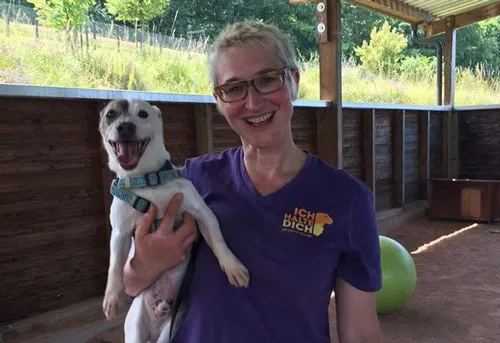 Mirjam Cordt im Ich-halte-Dich-Shirt hält lachend einen kleinen weißen Hund auf dem Arm