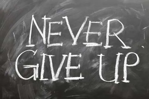 Kreideschrift Never Give Up auf einer Tafel als Sinnbild für Eric Hüthers Durchhaltevermögen
