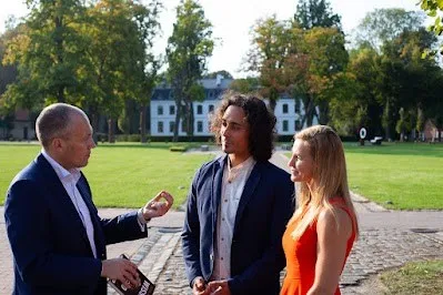 Oliver Pott im Gespräch mit einem Mann und einer Frau im Park vor einem Schloss
