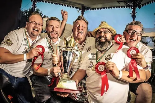 Das Grill-Team BBQ Wiesel jubelt mit Pokal und Siegerschleifen über den Weltmeistertitel