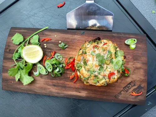Gegrilltes Gericht mit Kräutern, Limette und Chili auf einem Holzbrett – Online Grillkurs