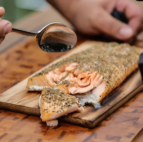 Gegrillter Lachs mit Kräuterkruste auf einem Holzbrett aus dem Online Grillkurs