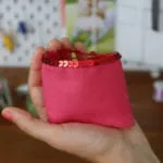 Hand hält ein kleines pinkes Täschchen mit Pailletten, genäht im Overlock Nähkurs Liebe deine Ovi