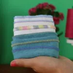 Stapel aus mit der Overlock gesäumten Handtüchern vor grünem Hintergrund