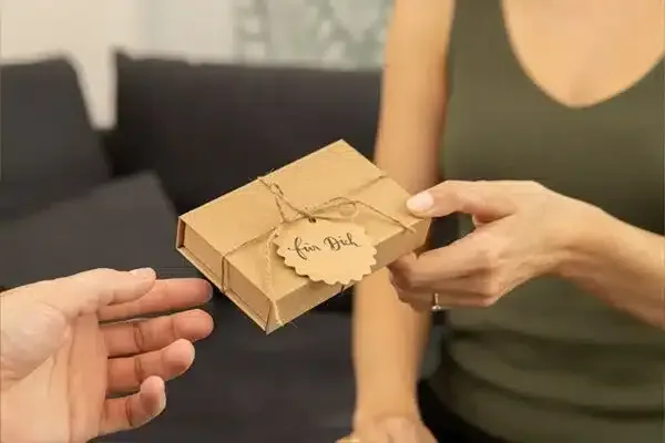 Eine Frau überreicht eine Geschenkbox von magoody mit dem Anhänger für Dich