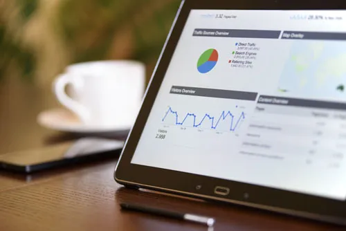 Tablet mit Traffic-Statistiken neben einer Kaffeetasse – Symbolbild für Erfahrungen mit dem Premium Affiliate Club