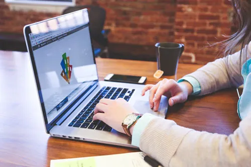 Person arbeitet am Laptop an einem Holztisch – Symbolbild für das Affiliate-Business mit dem Premium Affiliate Club