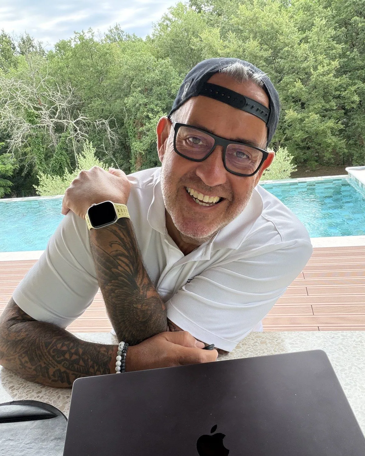Ralf Schmitz mit Laptop am Pool, Basecap und Brille