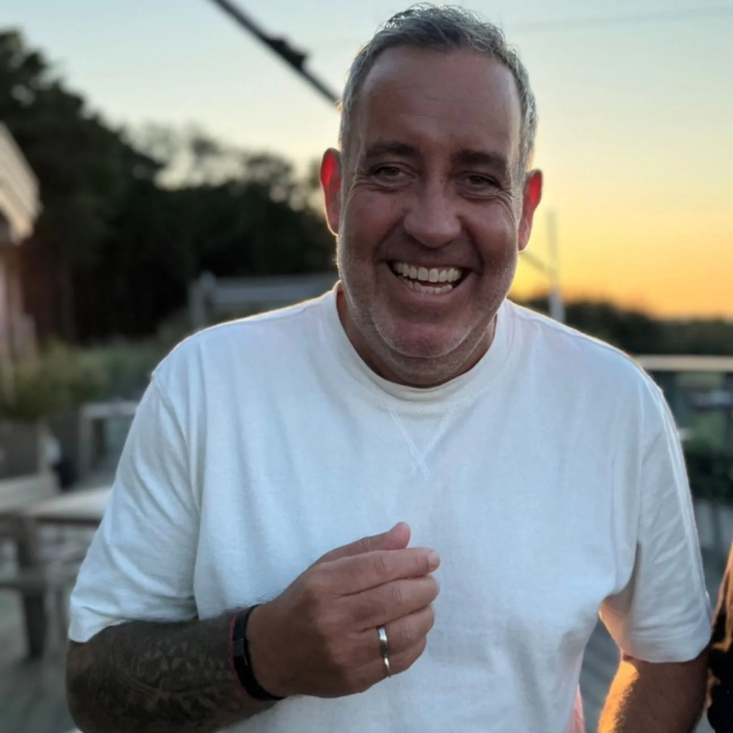 Porträt von Ralf Schmitz, einem der beiden Macher von TikFluencer, im weißen T-Shirt vor einem Sonnenuntergang