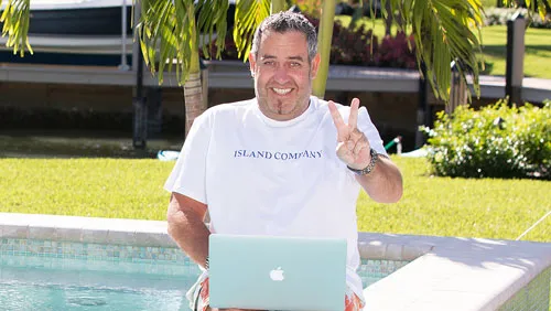 Ralf Schmitz am Pool mit Laptop auf den Knien zeigt ein Victory-Zeichen